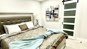 A bedroom with a tufted headboard, a bed with patterned bedding, a ceiling fan, and a sliding door.