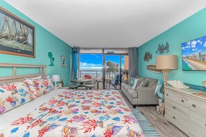 Habitación de hotel con cama, sofá, escritorio y vista al océano.