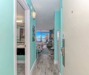 A hallway with a view to a balcony, a kitchen area, and a dining space.