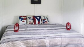 Ein Schlafzimmer mit einem Bett, Kissen mit puertoricanischen Flaggen und zwei roten Laternen.