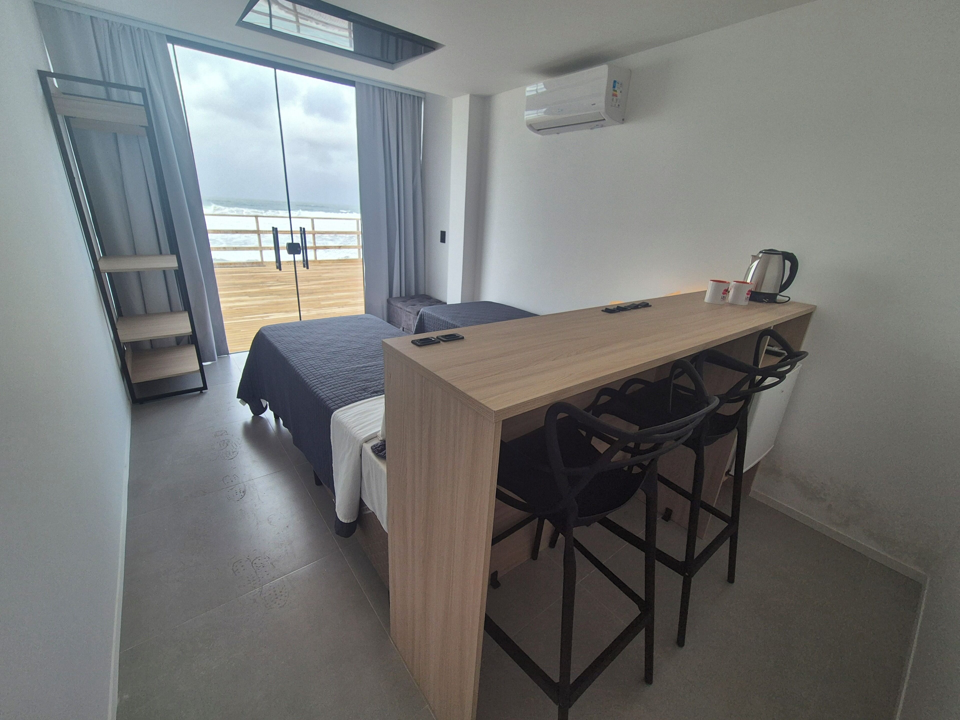 Huoneessa on sänky, työpöytä ja tuoli. Siellä on myös ikkuna, josta avautuu näkymä rannalle ja merelle.