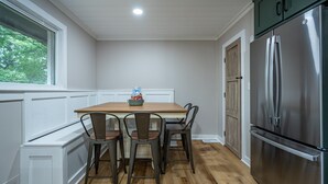 A kitchen with a wooden table, four chairs, a stainless steel refrigerator, and a window with a view of trees. - Comfort & Space in Prime Cartersville Spot (Cartersville)