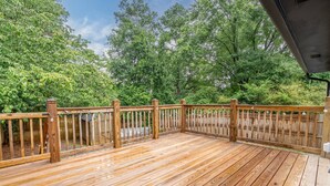A wooden deck with a metal railing, surrounded by trees. - Comfort & Space in Prime Cartersville Spot (Cartersville)