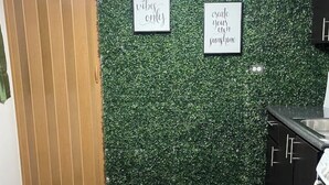 A kitchen with a wooden door, green wall with two framed signs, and a black countertop.