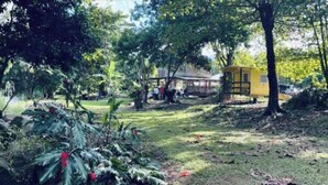 A park with a yellow structure, trees, and a grassy area.