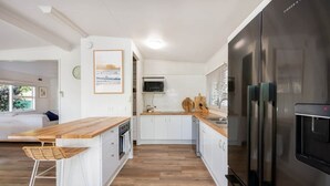 Una cocina moderna con armarios blancos, encimera de madera y refrigerador de acero inoxidable.