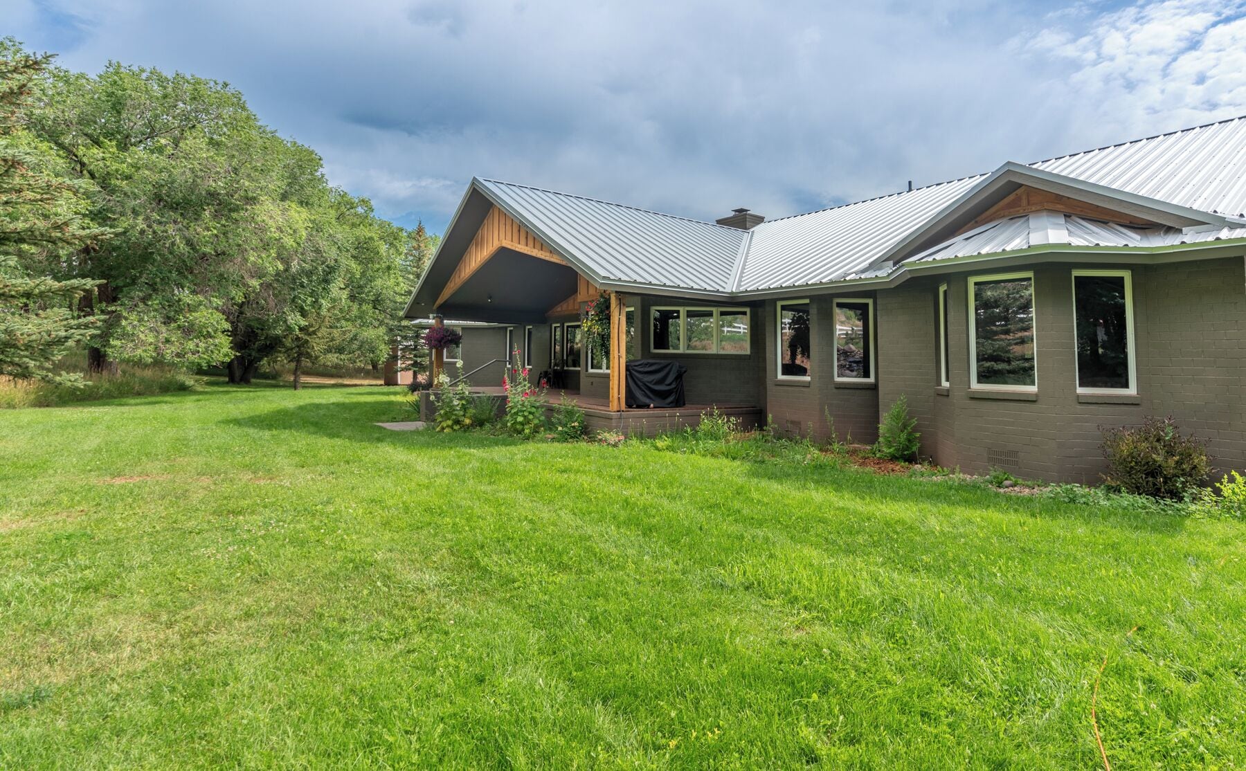 A modern house with a covered porch, large windows, and a well-maintained lawn.