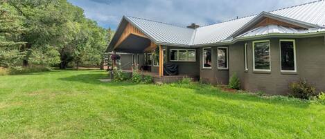 A modern house with a covered porch, large windows, and a well-maintained lawn.