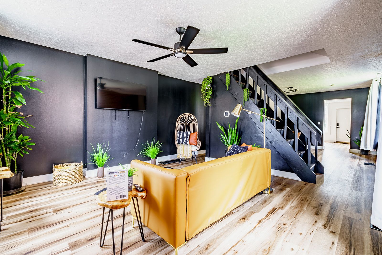 A modern living room with a sofa, a coffee table, a TV, and a staircase.