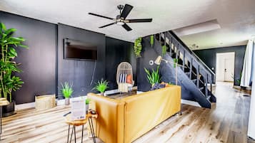 A modern living room with a sofa, a coffee table, a TV, and a staircase.