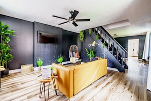 A modern living room with a sofa, a coffee table, a TV, and a staircase.