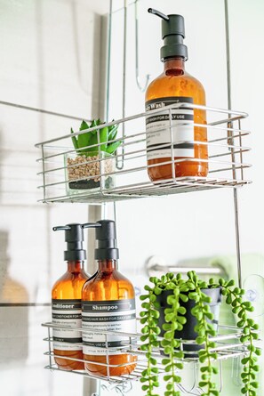 A bathroom shelf with toiletries including body wash, shampoo, and conditioner. - Jungle House Downtown Columbus – Modern Boutique Suites (Columbus)