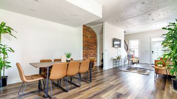 A modern dining area with a brick wall, a wooden dining table, and leather chairs.