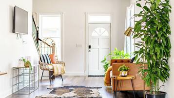 Una sala de estar con un sofá, una silla, una mesa de centro, un televisor y una planta grande en maceta.