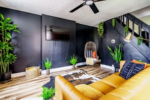 Una sala de estar moderna con un sofá, un sillón, un televisor y plantas.