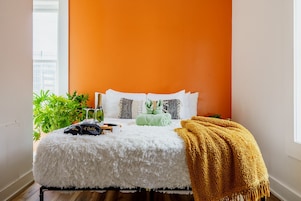 A bedroom with a bed, a green plant, a bottle, and a blanket.