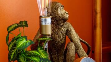 A monkey figurine, a light bulb, a speaker, and a plant on a wooden surface.