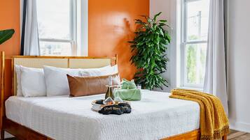 Een slaapkamer met een houten bed, twee ramen, een plafondventilator en een grote plant.