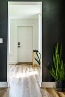A hallway with a white door, a wooden bench, and a potted plant.