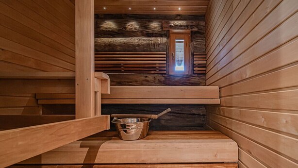 Uma sauna de madeira com uma bacia de metal e um banco de madeira.