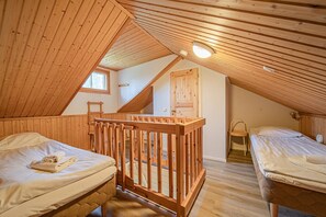 Acogedor dormitorio en ático con dos camas, barandillas de madera y techo inclinado.