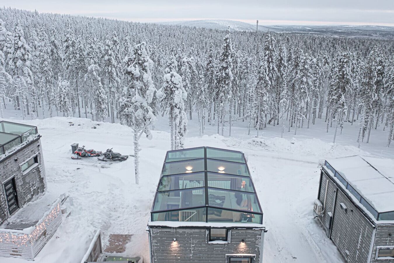 A modern building with a glass facade, surrounded by a snowy forest.