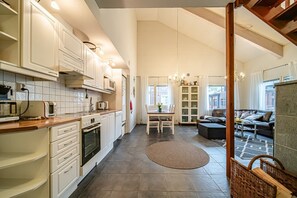 A spacious kitchen with modern appliances, a dining area with a table and chairs, and a cozy living room with a sofa and a fireplace.