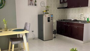 A modern kitchen with a dining area, featuring a refrigerator, cabinets, and a dining table with a bench. - Relax in Neiva: Modern apartment with bathtub close to Clinica Abner Lozano (Neiva)