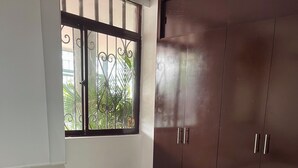 A bedroom with a bed, white bedding, a window with metal bars, and a dark wooden wardrobe. - Relax in Neiva: Modern apartment with bathtub close to Clinica Abner Lozano (Neiva)