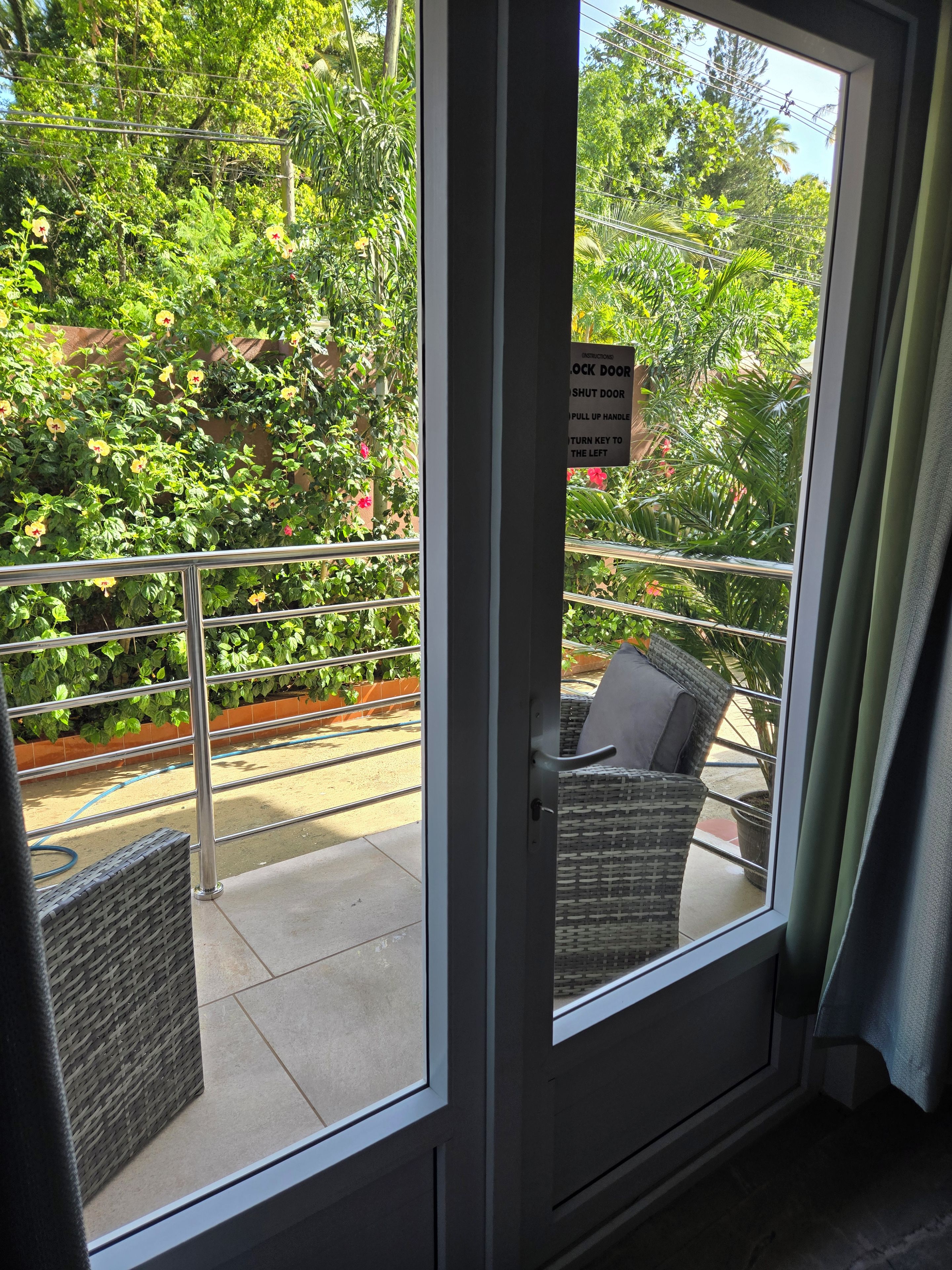 A room with a sliding glass door leading to a balcony with a metal railing and wicker furniture.