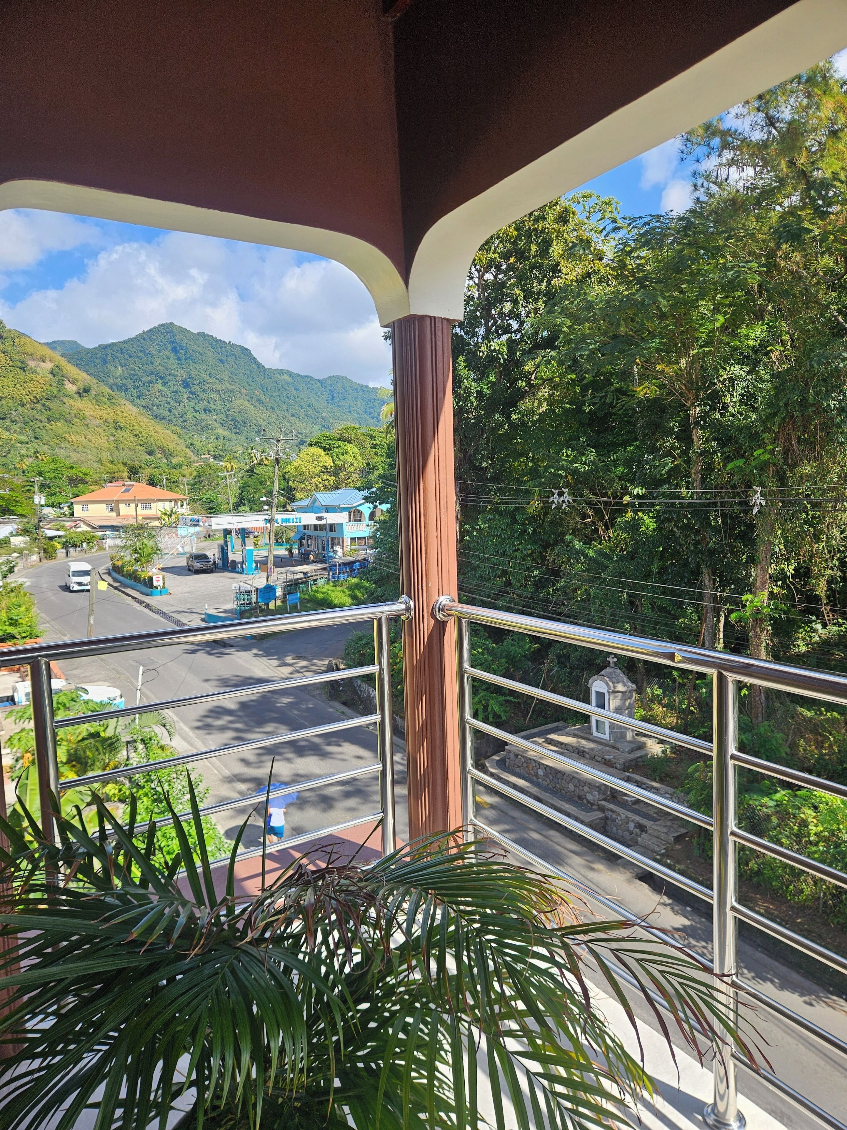 A balcony with a view of a road, a gas station, and a mountain.