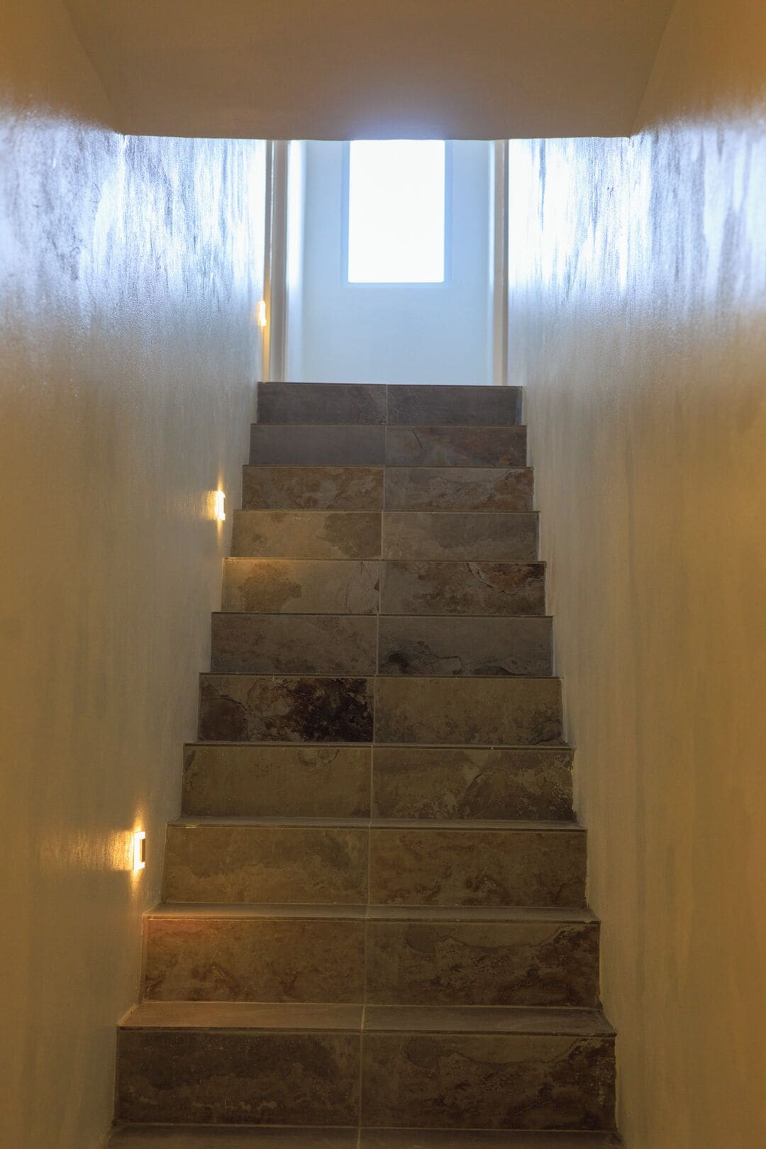 Una escalera de piedra conduce a una puerta con un ventanal encima.