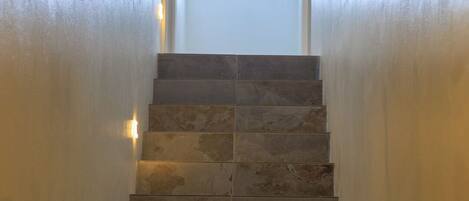 Una escalera de piedra conduce a una puerta con un ventanal encima.