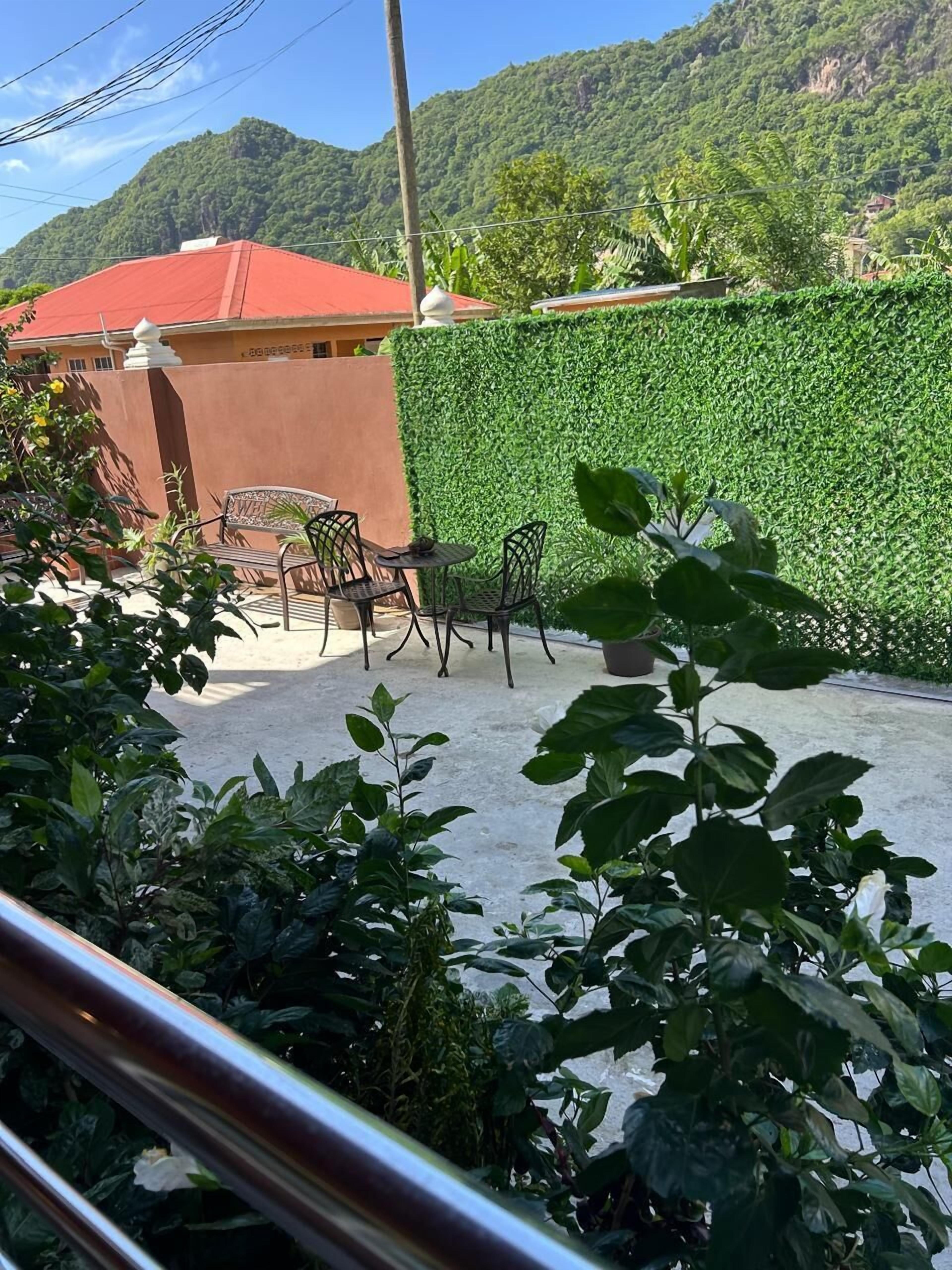 A patio area with outdoor seating, a green hedge, and a view of a mountain.