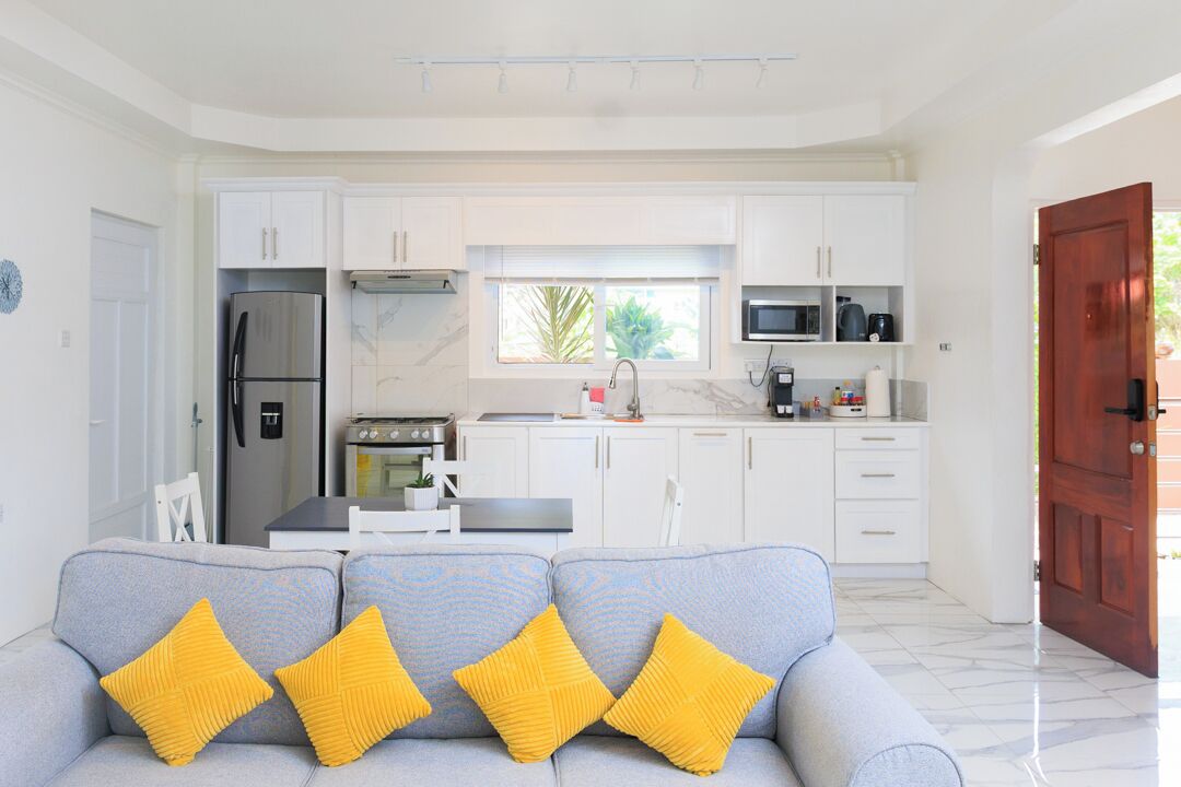 A modern kitchen with white cabinets, a stainless steel refrigerator, a microwave, and a stove.