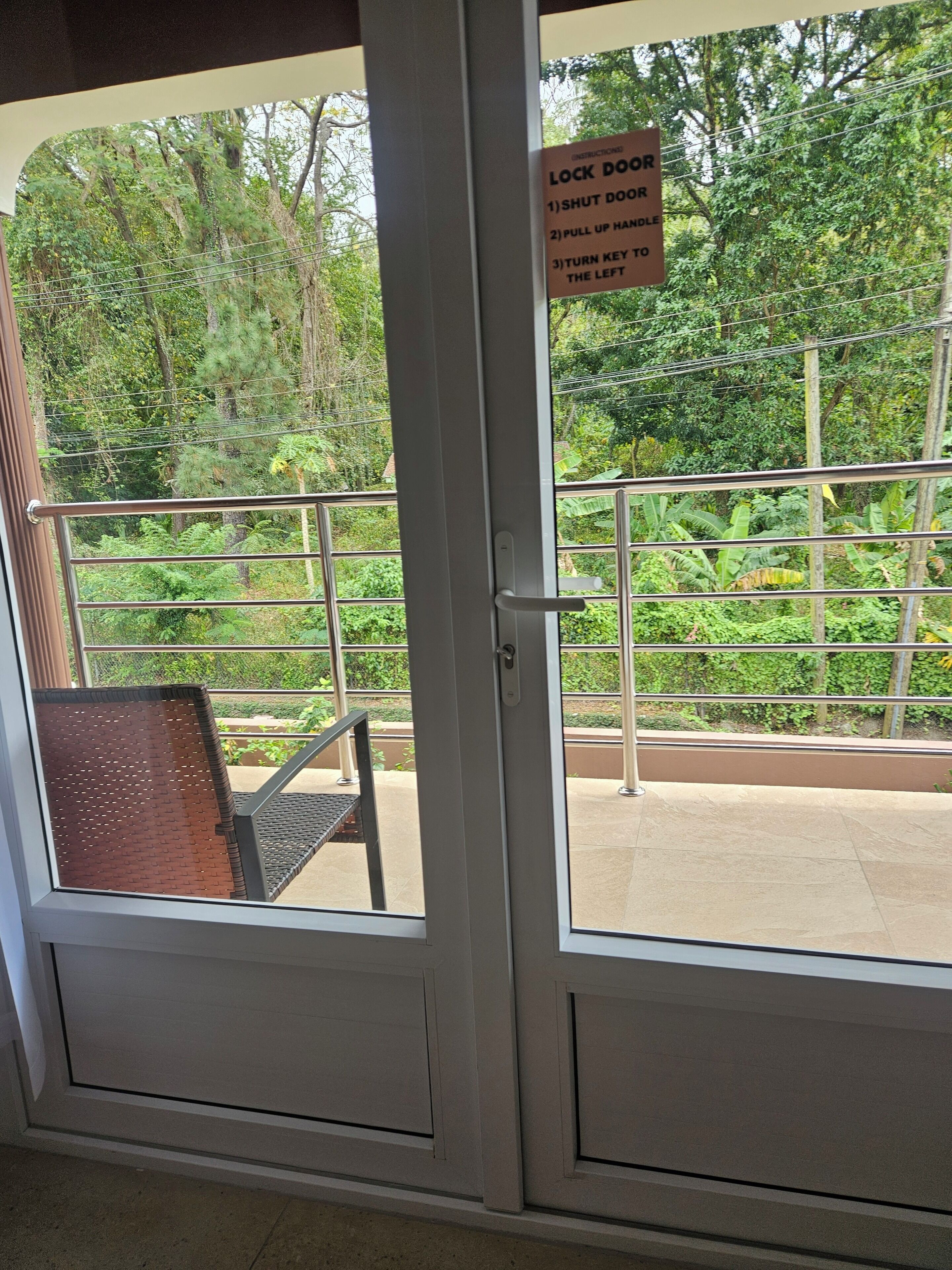 A view from inside a room through a glass door, with a sign instructing to lock the door, pull up the handle, and turn the key to the left.