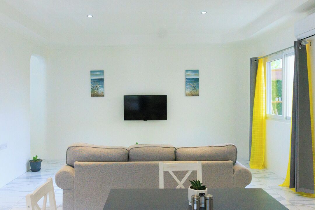 A living room with a sofa, a flat-screen TV, and two wall-mounted paintings.