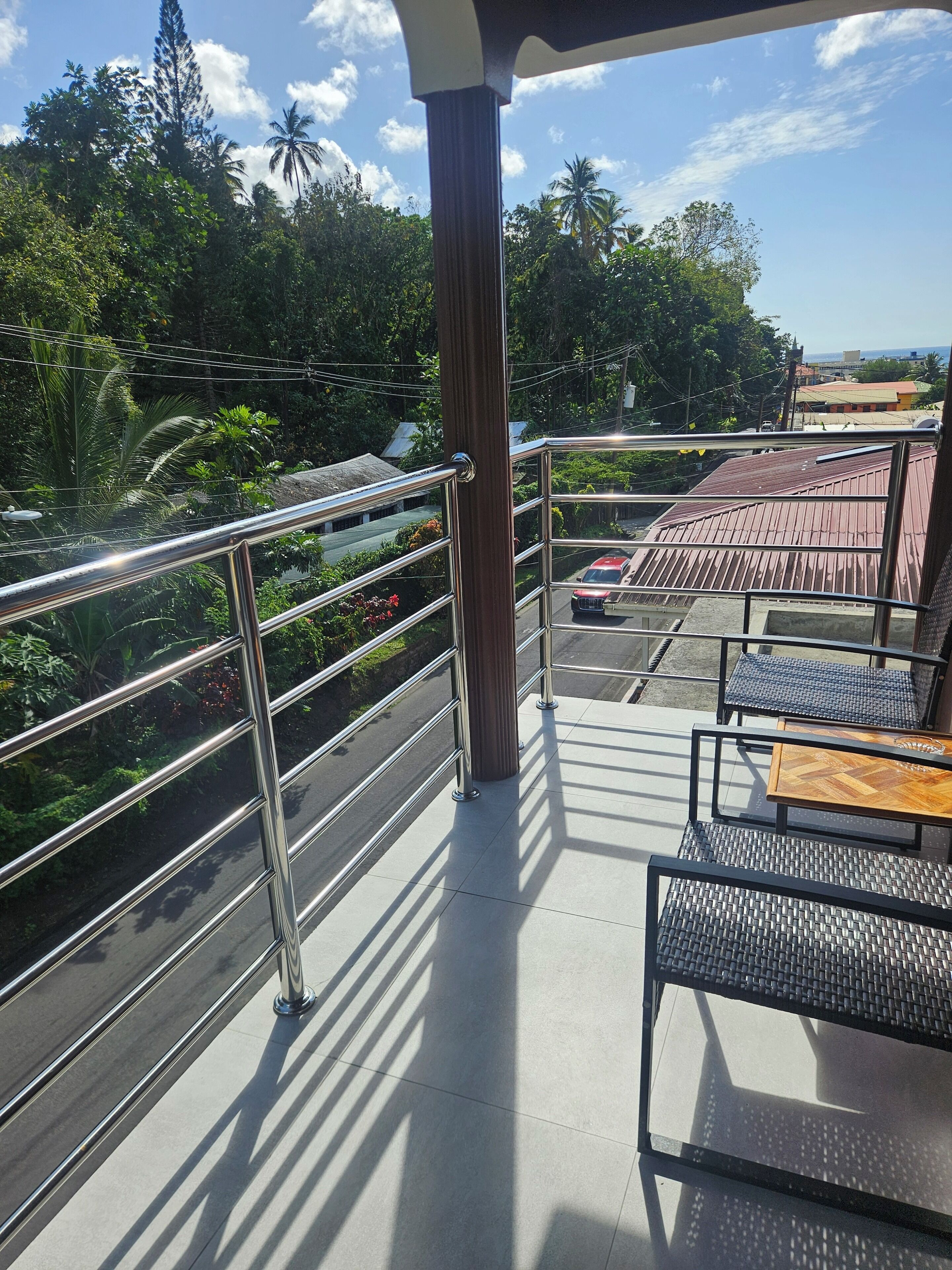 A balcony with metal railings, a wooden table, and a chair.