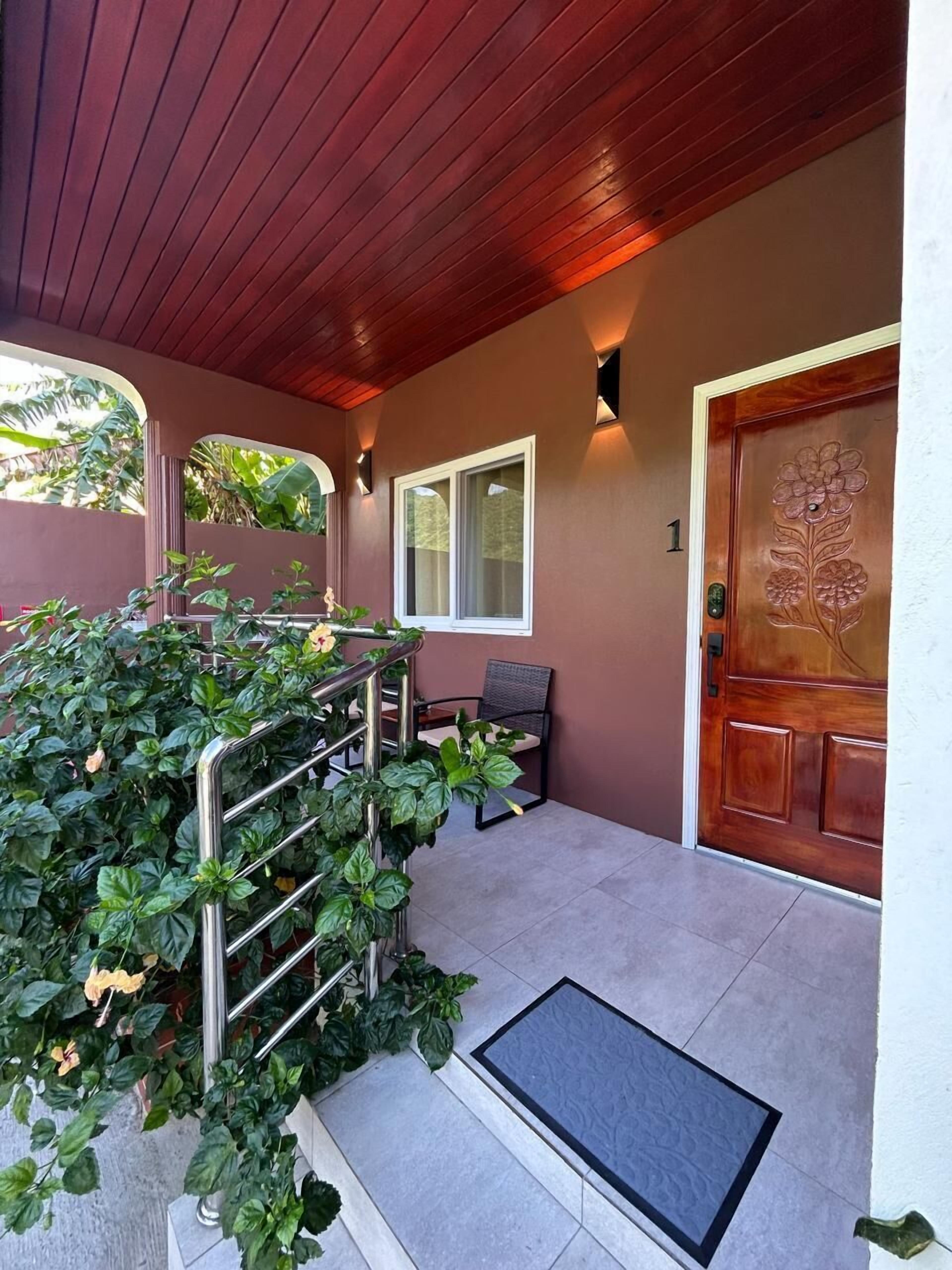 A covered porch with a wooden door, a window, and a metal railing.