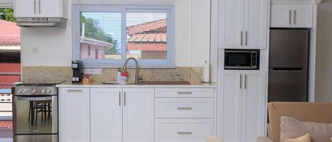 A modern kitchen with white cabinets, a stainless steel stove, a microwave, and a refrigerator.
