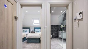 A bedroom with a bed, a bedside table, and a window. - SOBO Loft Southborne Grove +Beach Deluxe Apartment (Southbourne)