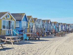 Una hilera de casas de playa con terrazas de madera y mobiliario exterior.