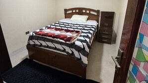 A bedroom with a bed, a bedside table, a wardrobe, and a door with a colorful pattern. - Krass casa de huespedes (Sucre)