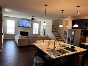A modern kitchen with a central island, stainless steel appliances, and a dining area with a sofa.