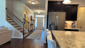 A modern kitchen with dark cabinets, a granite countertop, and a stainless steel refrigerator. - Spacious LUXE Home in RTP / near Airport (Durham)