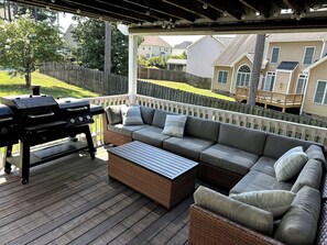 An outdoor deck with a grill, a sofa, and a coffee table.