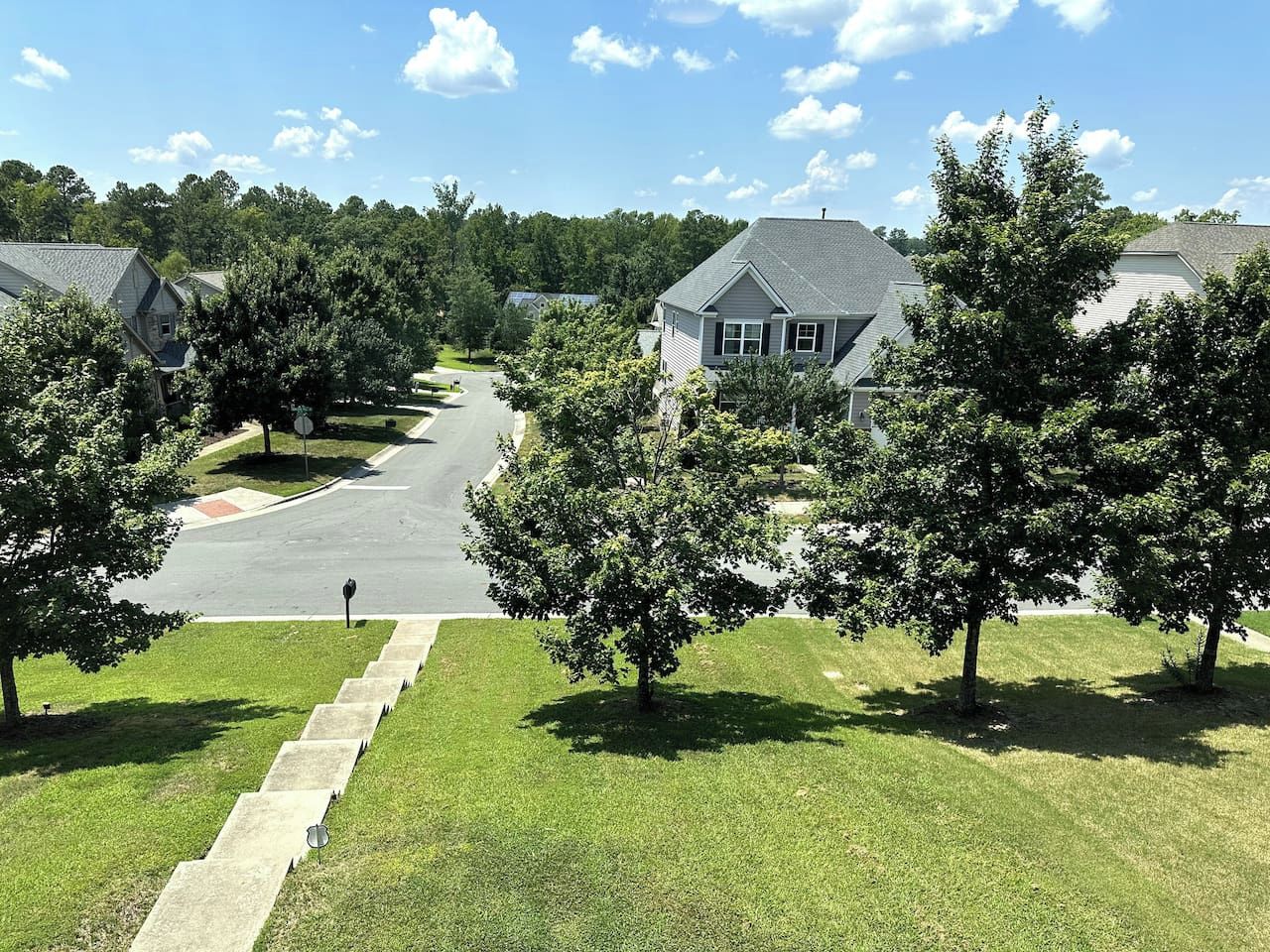A residential street with houses, a sidewalk, and trees.