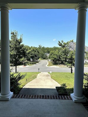 A covered porch with a view of a residential street.