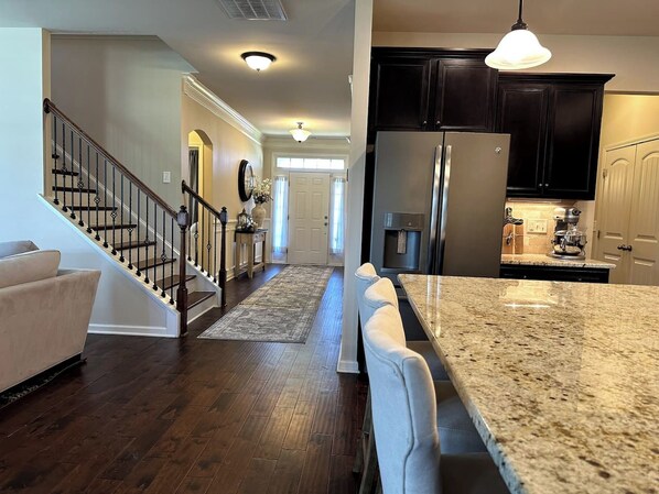 A modern kitchen with dark cabinets, a stainless steel refrigerator, and a granite countertop.