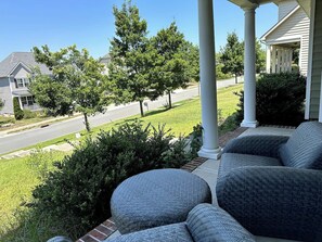 A porch with outdoor seating and a view of a residential street. - Spacious LUXE Home | RTP/Airport (Durham)